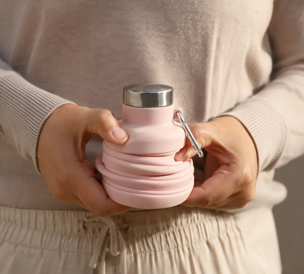 Two hands twisting a Blush collapsible bottle closed along its rings