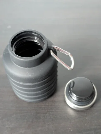 Collapsible bottle with the stainless-steel cap unscrewed beside it