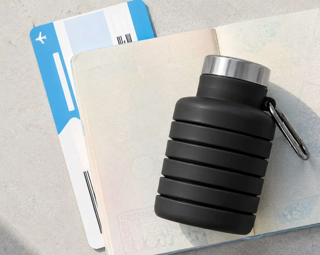A folded Black collapsible bottle resting on a passport and travel documents